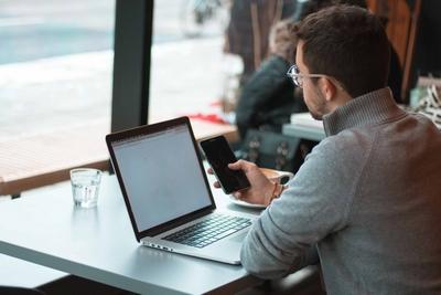 Image of man using laptop and phone